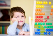 Ein Junge im Grundschul- oder Kindergartenalter schaut skeptisch auf einen Rechenschieber.