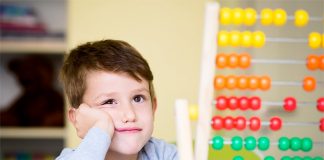 Ein Junge im Grundschul- oder Kindergartenalter schaut skeptisch auf einen Rechenschieber.
