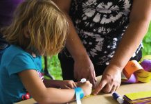 bastelndes Kind mit Helferin