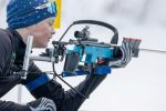 Jugendlicher Biathlet im Schnee lädt sein Gewehr.