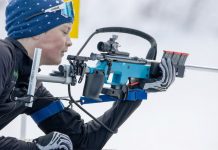 Jugendlicher Biathlet im Schnee lädt sein Gewehr.