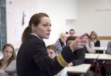 Junge Frau in Marineuniform doziert in einer Schulklasse.