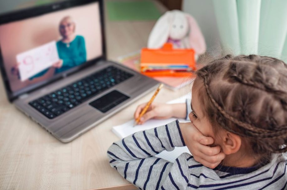 gelangweiltes Mädchen vor einem Laptopbildschirm mit Lehrerin