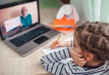 gelangweiltes Mädchen vor einem Laptopbildschirm mit Lehrerin