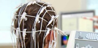 Studie zeigt stärkere Gehirnvernetzung beim Handschreiben als beim Tippen Junge mit Elektroden am Kopf von hinten, im Hintergrund Apparaturen und ein Bildschirm