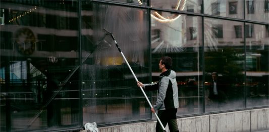 Junger Mann Schaufensterscheiben putzend