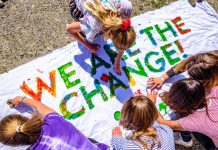 Jugendliche schreiben "we are the change" auf ein Plakat.