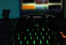 Gamepad auf einer Tastatur mit grüner Beleuchtung, im Hintergrund ein Bildschimr