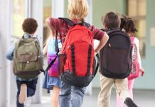 Auf einem Gang rennende Grundschülerinnen und Schüler von hinten.