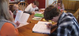 Lernen am Küchentisch: vier Kinder verschiedenen Alters in Hefte schreibend