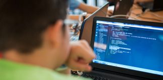 Schüler blicken auf Bildschirme mit Codezeilen