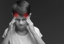 Das unterschätzte Leid: Zwei Drittel der Schüler klagen regelmäßig über Kopfschmerzen Schwarzweißbild eines Jungen, der sich die Finger an die Schläfen hält, von wo aus zwei rote Punkte über seinen Kop ausstrahlen.