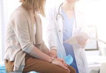 Versuchen Lehrer, sich vor dem Unterricht zu drücken? Ärzte behaupten das Eine PAtientin sitzt quer auf einer Behandlungsliege, von der Seite fasst eine Ärztin an ihren Puls während sie die auf einem Diagnosezettel geschriebene Behandlung erläutert.