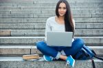 Junge Frau mit Laptop auf einer Treppe.