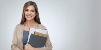 Ihr Schuljahresplaner, individuell gedruckt nach Ihren Wünschen – jetzt mit 20 % Rabatt lächelnde Junge Frau mit Heften und eienn Block im Arm vor grauem Hintergrund