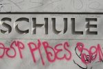 mit Grafitti beschmiertes Schuleingangsschild