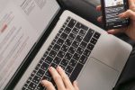Person bedient gleichzeitig Laptop und Smartphone