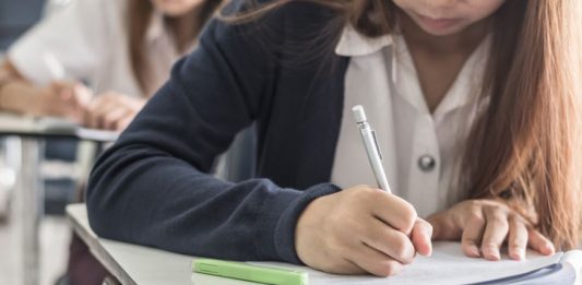 Schreibende Mädchen an Einzeltischen