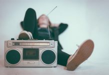 Junger Mann liegt hinter einem Kofferradio.