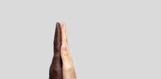 Zwei zusammenklappende Hände verschiedener Hautfarben