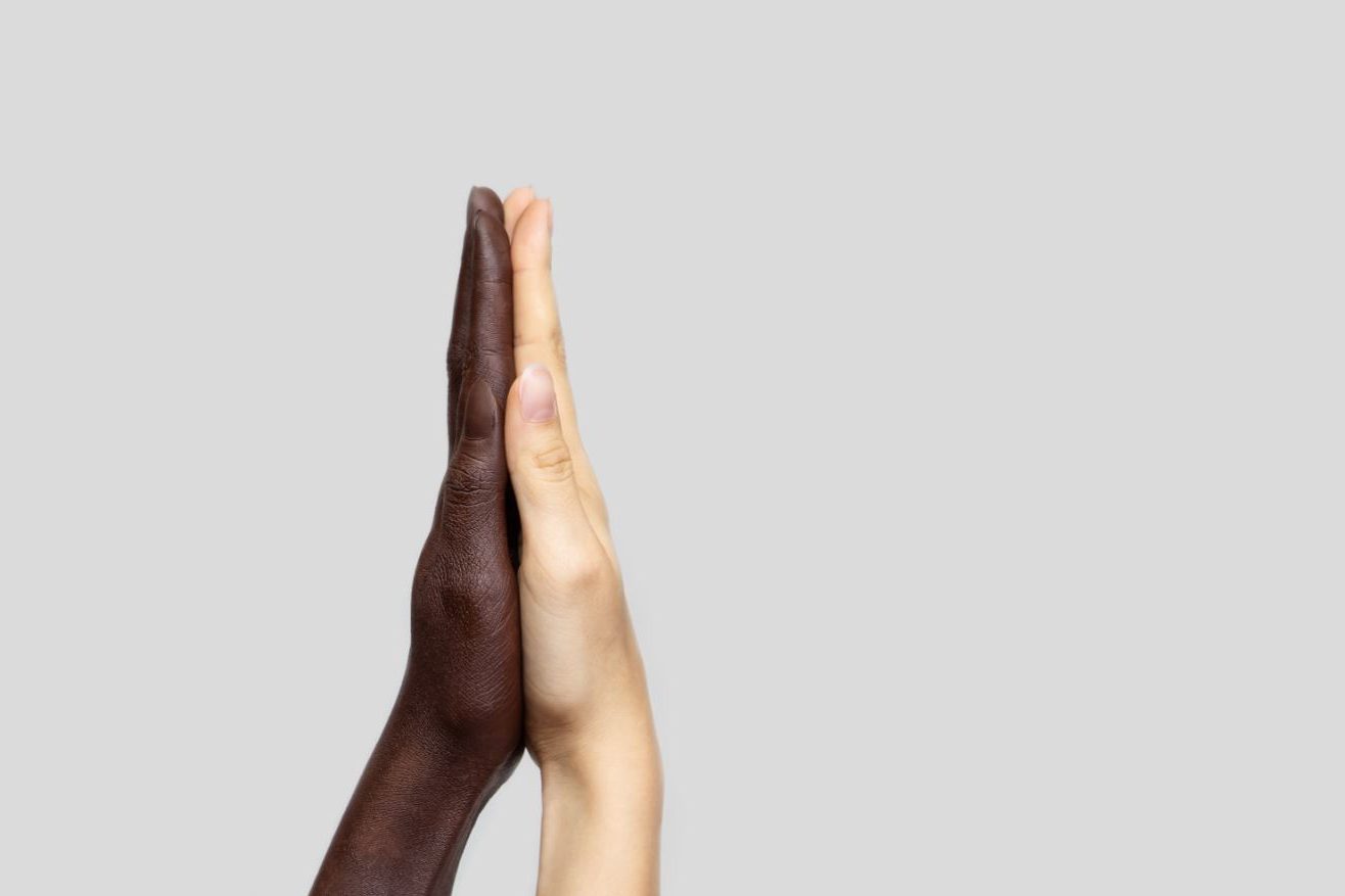 Zwei zusammenklappende Hände verschiedener Hautfarben
