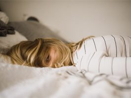 Eine junge Frau liegt auf dem Bett.