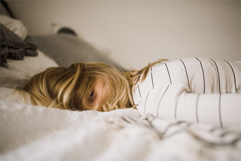 Eine junge Frau liegt auf dem Bett.