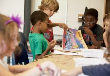 Grundschüler verschiedener Herkunft blättern gemeinsam in einem Comic.