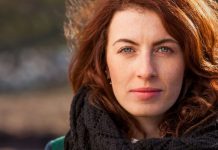 skeptisch in die Kamera blickende Frau mit Schal