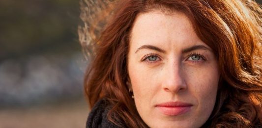 skeptisch in die Kamera blickende Frau mit Schal