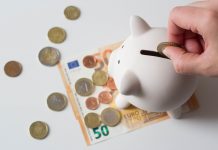 Sparschwein mit herumliegene Euro-Münzen und Scheinen