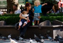 Tagesmutter mit zwei Kindern auf einer Parkbank