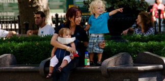 Tagesmutter mit zwei Kindern auf einer Parkbank