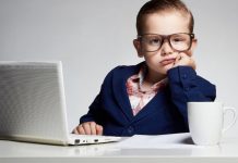 mit ANzug und Brille als Unternehmer verkleidetes Kind an einem Laptop