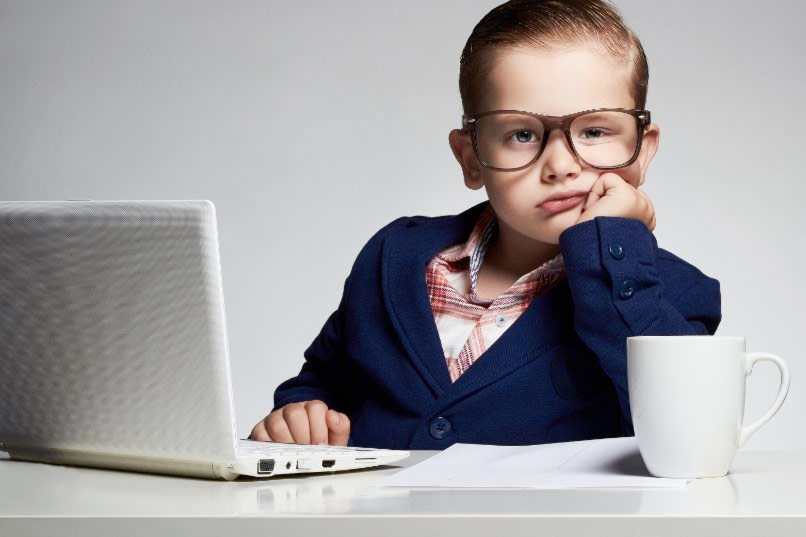 mit ANzug und Brille als Unternehmer verkleidetes Kind an einem Laptop