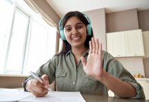 Von blinden Menschen lernen: Wie Zoom, Teams & Co externe Expert*innen in die Schule holen Junge Frau mit Kopfhörern blickt lächelnd und winkend in Kamera