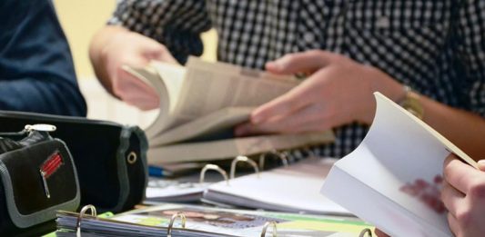 Großaufnahme dreier an enem Tisch lesender Studierender