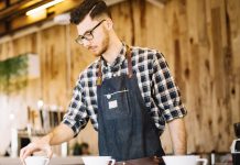 Junger Mann hinter einem Tresen, Kaffefilter ordnend