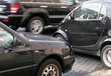 Umfrage: Viele Eltern halten den Schulweg ihrer Kinder nicht für sicher Längs- und querparkende Autos an einer Straße auf der ein weiteres Auto vorbeifährt.