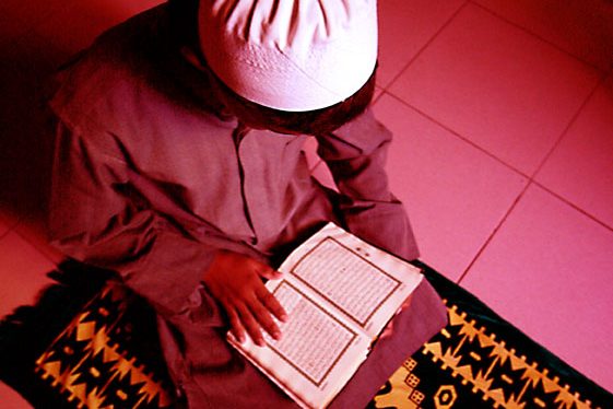 Ein junge mit weißer Kopfbedeckung liest in einem Buch.