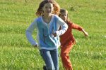 auf einer Wiese laufen 2 Kinder