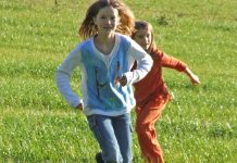 auf einer Wiese laufen 2 Kinder