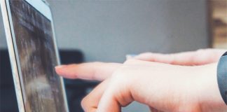 Finger zweier Hände deuten auf ein unerkennbares Detail auf einem Laptopbildschirm