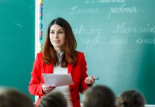 Ukrainische Lehrkräfte im Schuldienst willkommen – aber (bislang) nur deutschsprachige Lehrerin vor einer mit ukrainischen Sätzen beschriebenen Tafel.