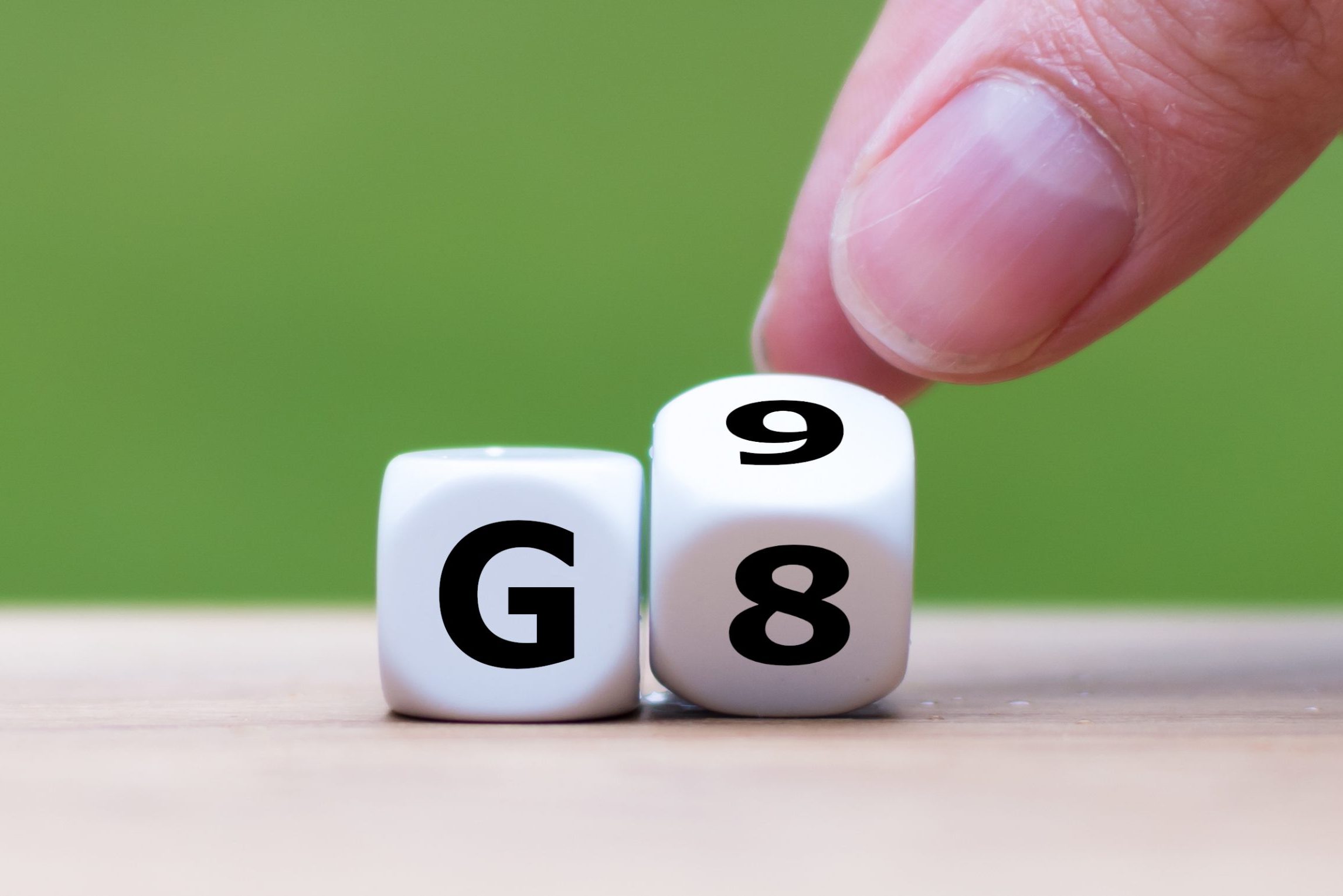 zwei Würfel nebeneinander. Sie zeigen links ein G, während der Rechte von zwei Fingern gerade von 8 auf 9 gedreht wird.