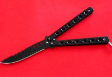 aufgeklapptes schwarzes Butterflymesser auf rotem Grund