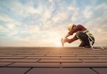 Dachdecker schraubt auf dem Dachfirst