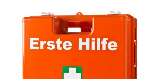 Erst Hilfe Koffer, orange mit weißem Kreuz auf grünem Grund