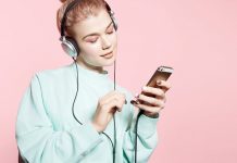 Lächelnde Frau mit Kopfhörern, die auf ihr Handy blickt.