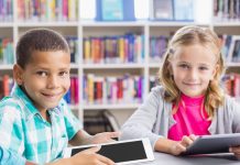 Junge, Mädchen mit Tablets in Schule, lächelnd.